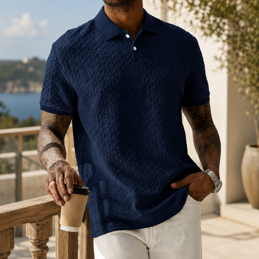 Polo bleu marine à maille texturée, homme appuyé sur une rambarde en pierre