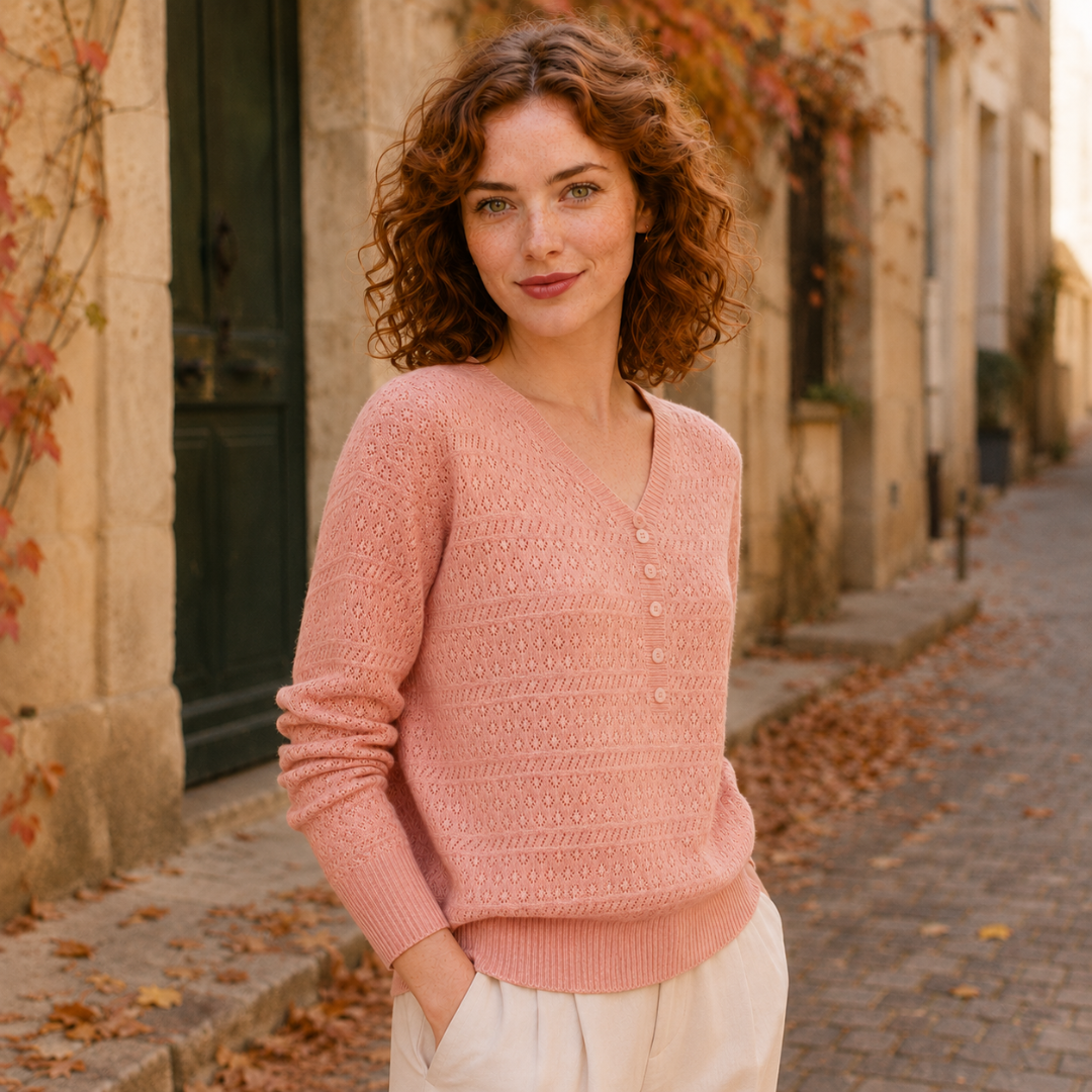 Pull rose ajouré porté de trois quarts, patte de boutons et bas côtelé visibles
