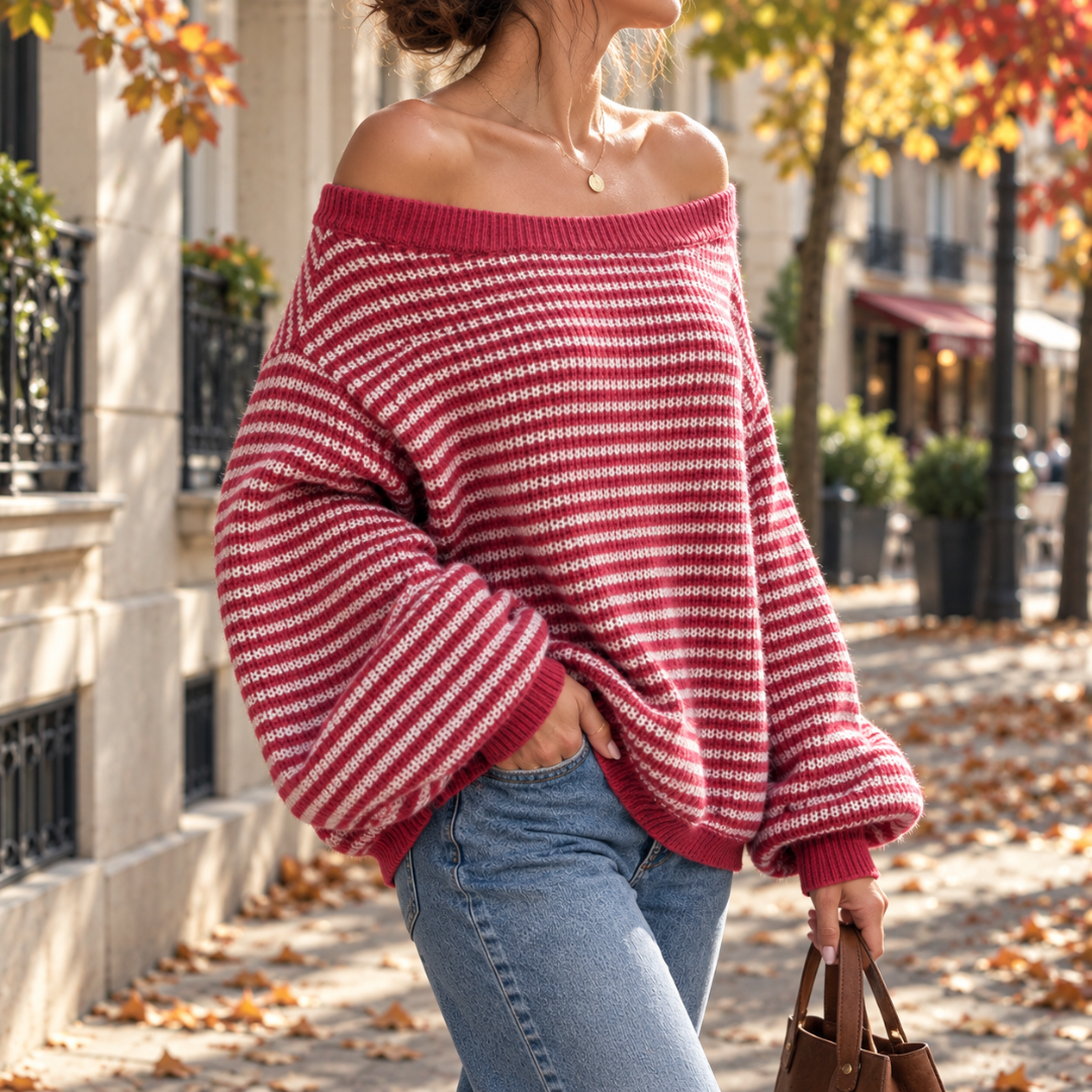 Pull rouge à fines rayures porté avec un pantalon clair, épaules dénudées