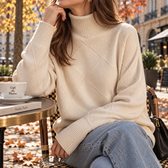 Pull femme beige à col roulé et losanges en relief, porté en terrasse