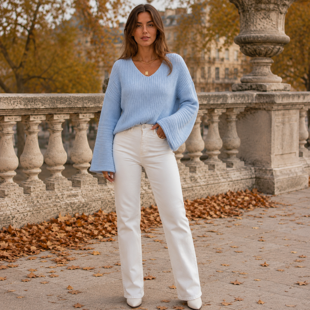 Pull femme bleu clair en maille côtelée, col V et manches évasées, porté avec un pantalon blanc