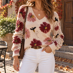 Pull femme fleuri rouge porté avec un pantalon blanc et une ceinture marron
