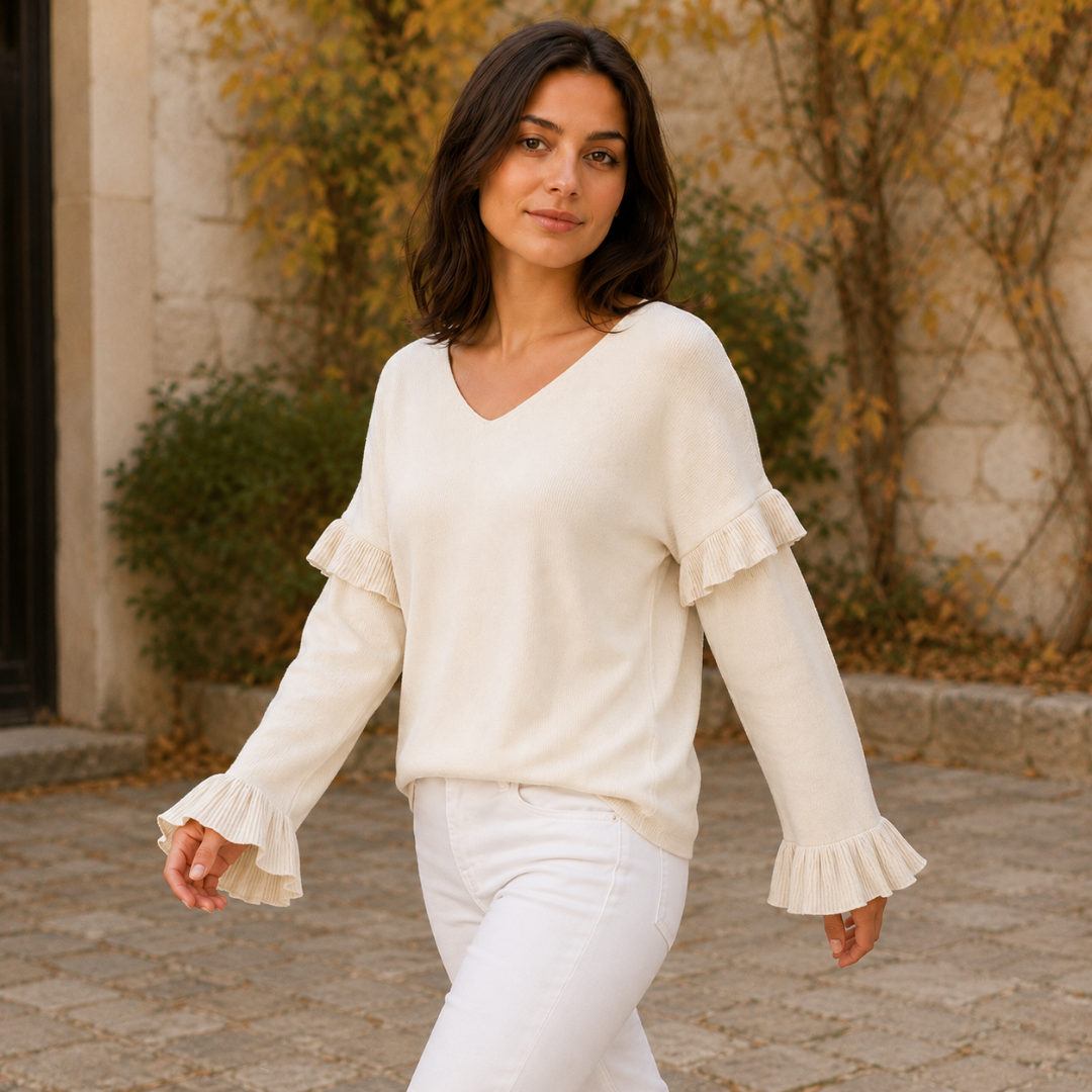 Pull femme blanc col V, poignets plissés évasés visibles sur les deux manches