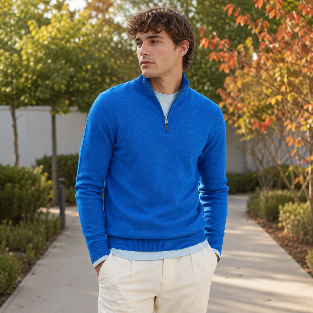 Pull homme bleu vif à demi-zip et poignets côtelés dans une allée bordée d'arbustes