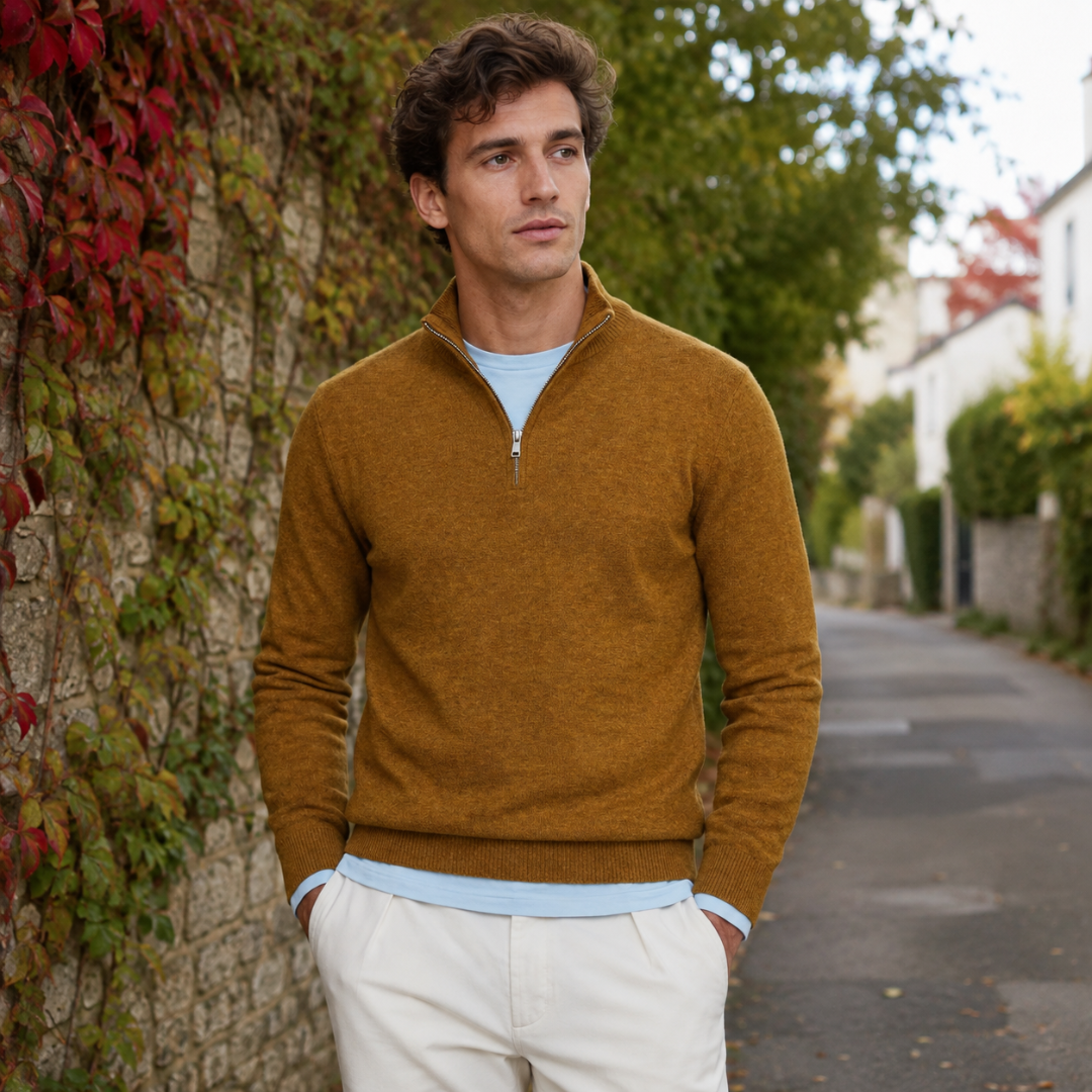 Pull homme kaki à col montant et fermeture demi-zip devant un mur végétalisé