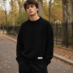 Pull homme noir en maille texturée avec étiquette blanche sur le bas côtelé