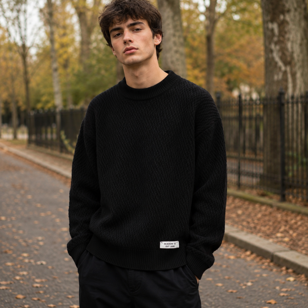 Pull homme noir en maille texturée avec étiquette blanche sur le bas côtelé