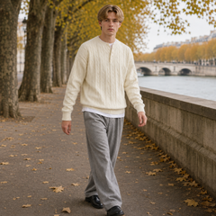 Homme en marche portant le pull blanc torsadé et un pantalon gris large