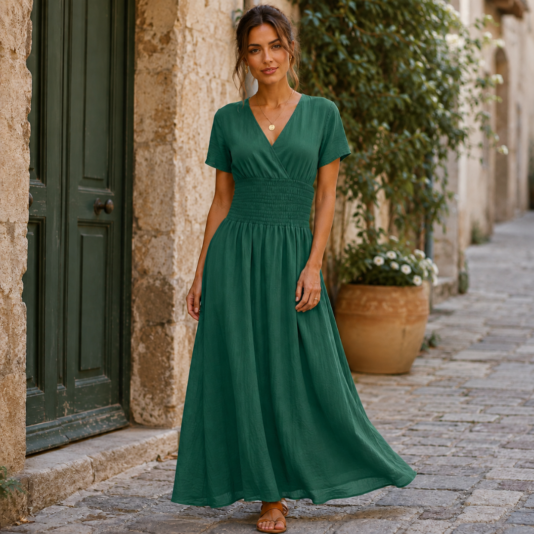 Robe longue verte à col V croisé, jupe fluide et évasée devant une porte