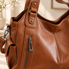 Gros plan sur le zip latéral et les surpiqûres du sac marron effet cuir