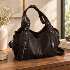 Sac bandoulière femme marron foncé posé sur une table, double anse et zips argentés