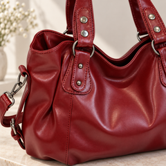Gros plan du sac rouge montrant anneaux, rivets et plis souples du côté