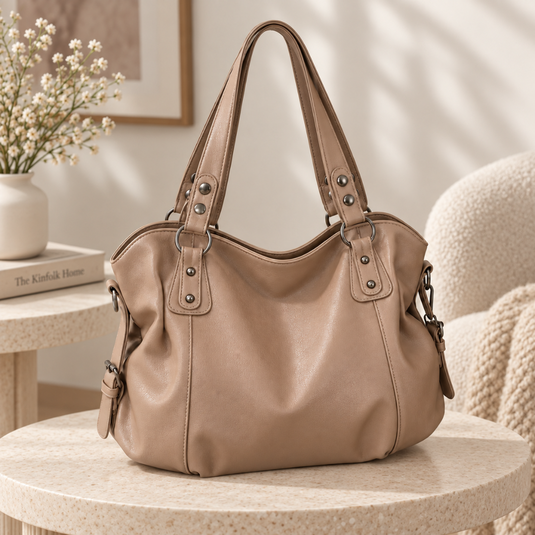 Sac à main taupe effet cuir sur une table ronde, anses doubles cloutées