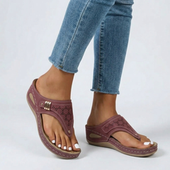 Sandales compensées rouge portées avec jean, motifs ajourés et lanière tong visibles