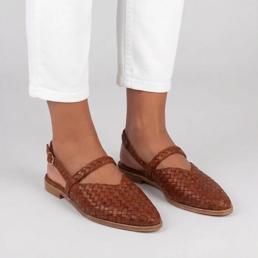 Sandales plates tressées femme marron portées de trois quarts avec pantalon blanc