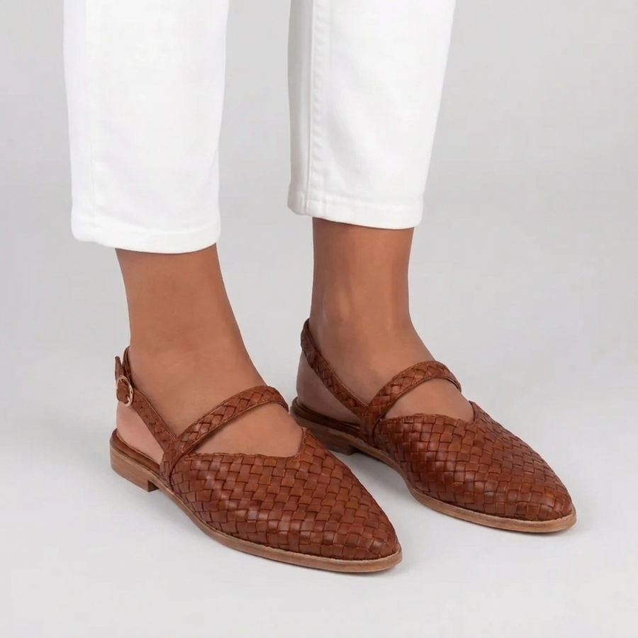 Sandales plates tressées femme marron portées de trois quarts avec pantalon blanc