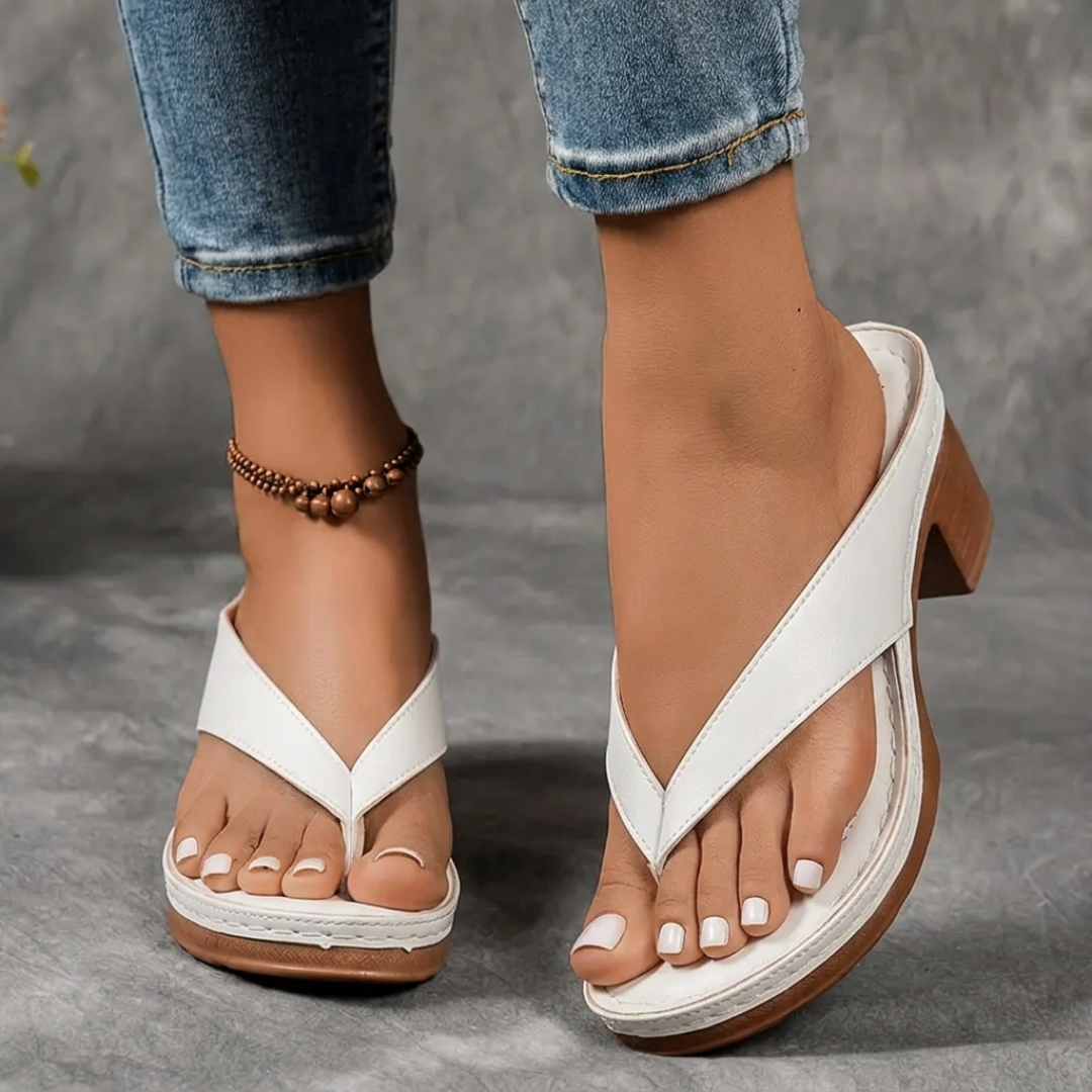 Détail pied chaussé d'une sandale blanche à talon carré