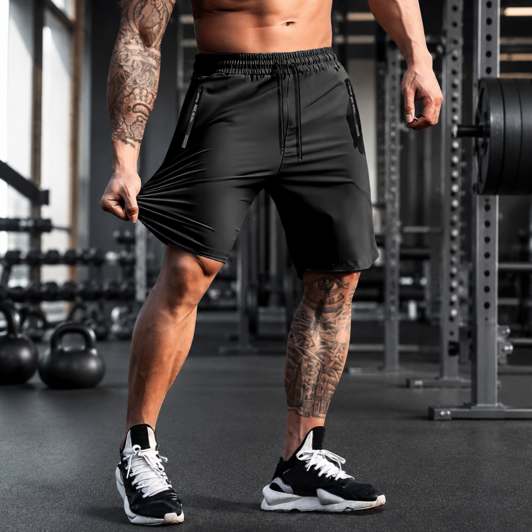 Short de sport homme noir avec poches zippées, vue de face en salle de musculation