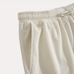 Détail du motif texturé beige et de la ceinture froncée du short homme
