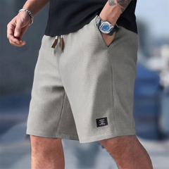 Short homme casual gris porté, taille élastique et poche latérale