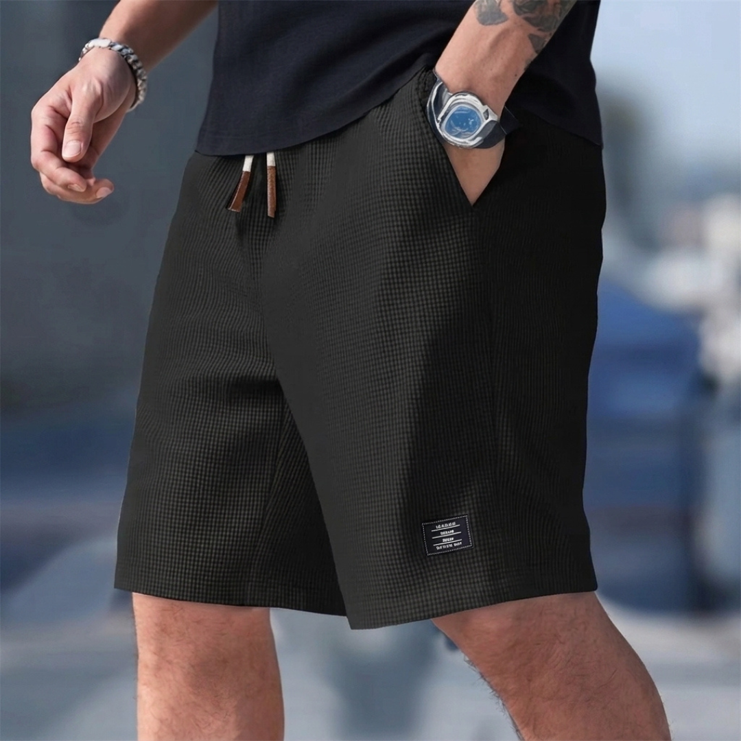 Short homme casual noir porté avec cordon de serrage et étiquette latérale