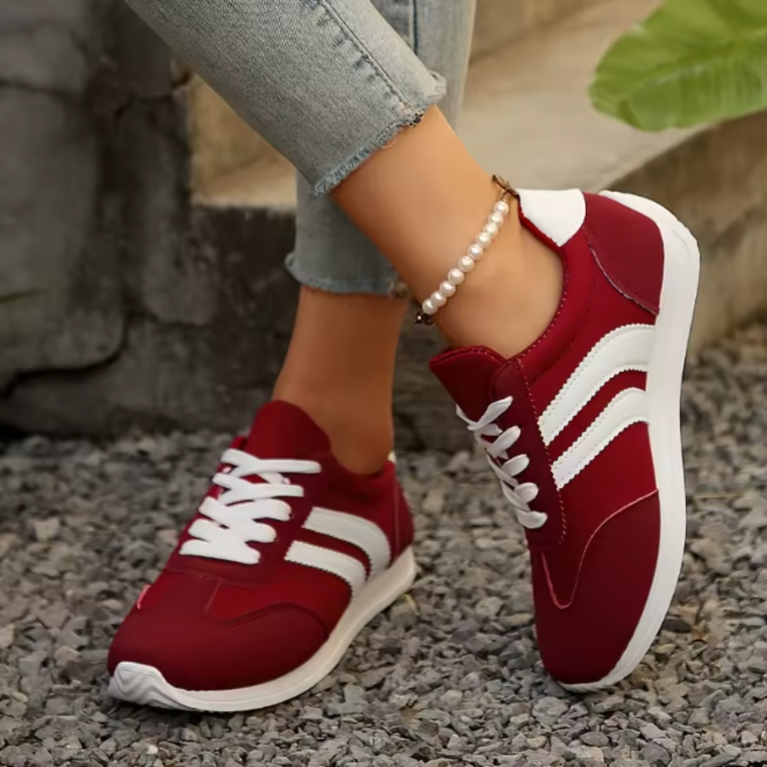 Vue de côté des sneakers rouges avec bandes blanches sur fond extérieur