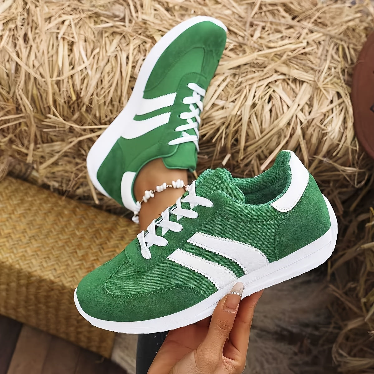 Paire de sneakers vertes posée de face sur fond naturel