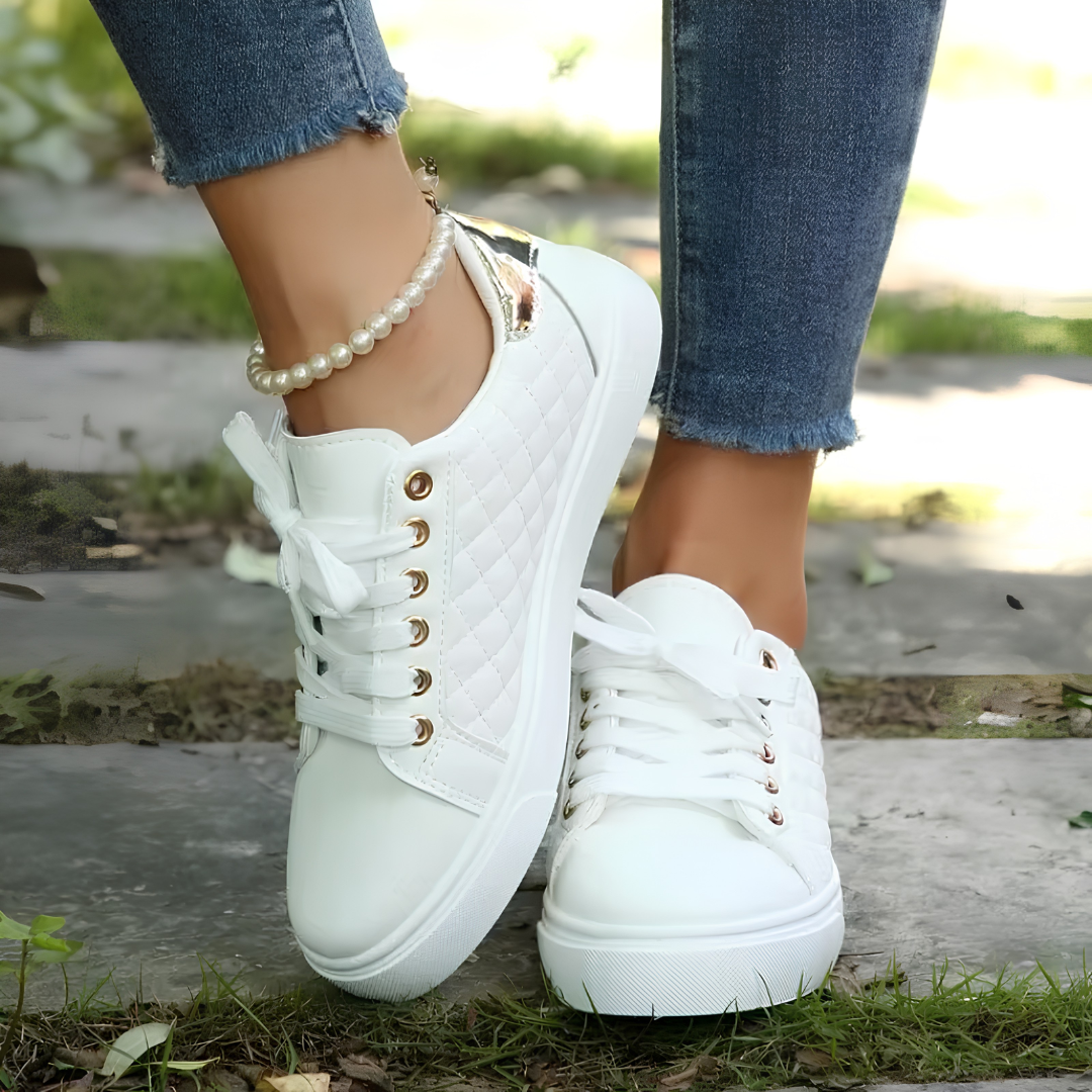 Paire de sneakers blanches Clarice posée sur fond extérieur, vue du dessus légèrement