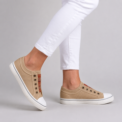 Sneakers beige sans lacets en toile portées avec pantalon blanc, vue de profil
