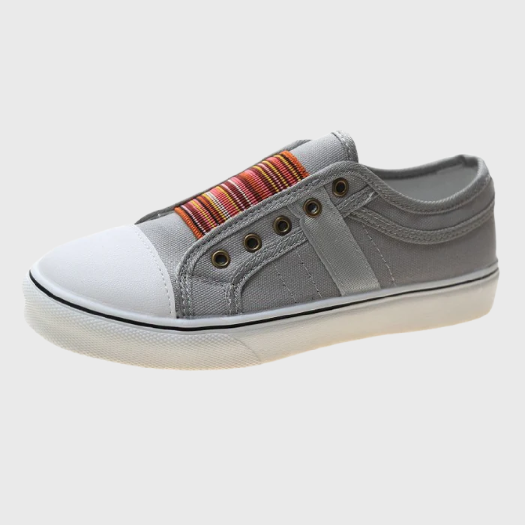 Paire de sneakers grises portées avec jean, détail élastique coloré