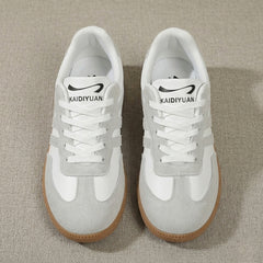 Vue de dessus des deux sneakers beige et blanc posées au sol, lacets blancs plats