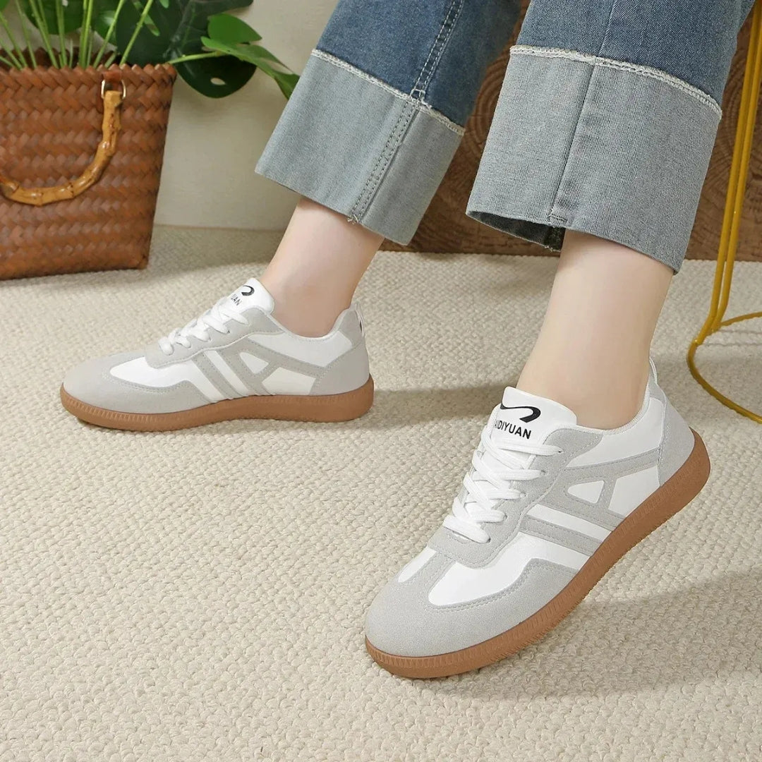 Sneakers femme blanc cassé portées avec un jean retroussé, vue de profil gauche