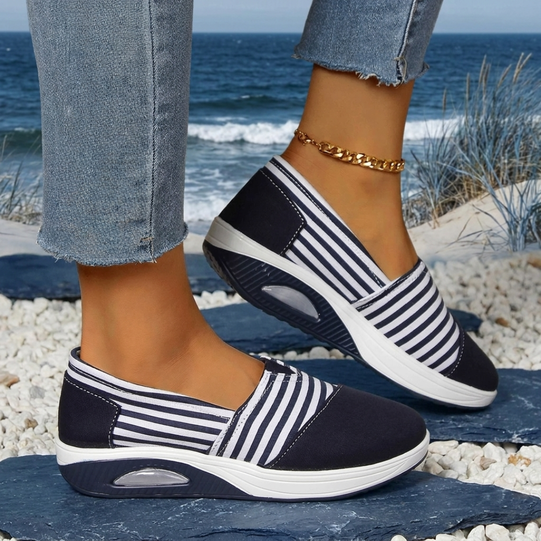 Sneakers slip-on bleu marine rayées blanches portées au bord de la mer