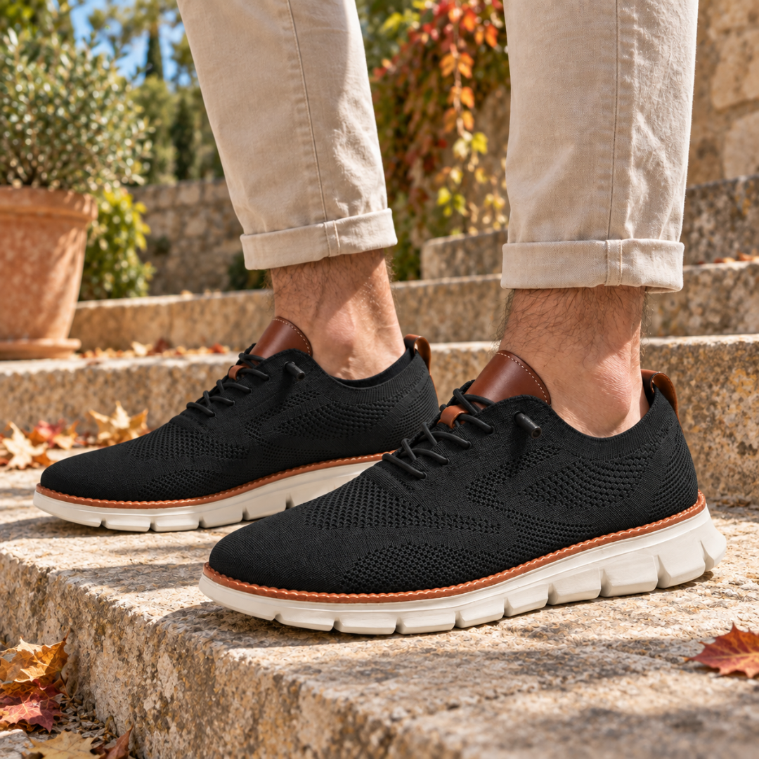 Sneakers homme noires ajourées avec empiècement marron au talon, portées dans un escalier