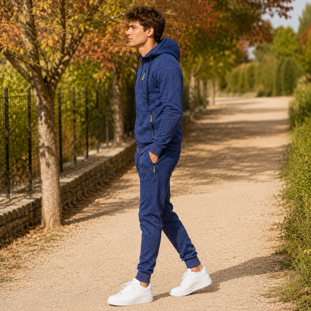 Survêtement homme bleu de profil, veste à capuche zippée et poche zippée contrastante