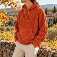 Sweat homme orange côtelé porté avec un pantalon beige, poche kangourou visible