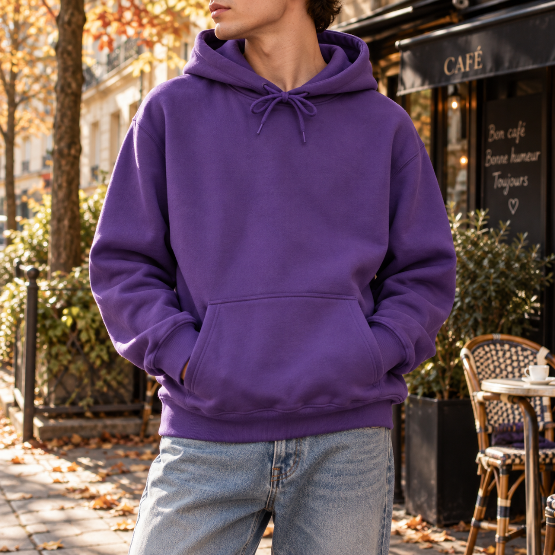 Sweat à capuche homme violet porté avec un pantalon clair devant un café