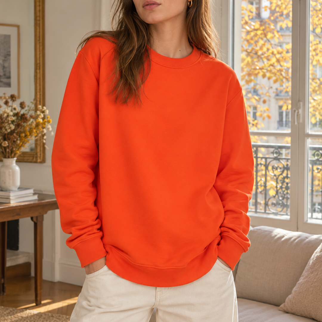 Sweat femme orange vif à col rond côtelé, porté avec un pantalon crème