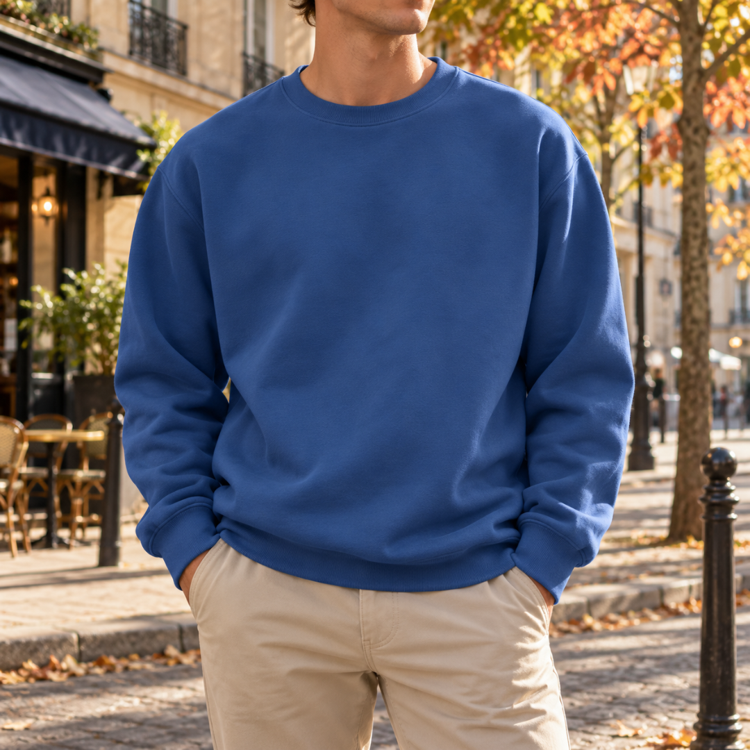 Sweat homme bleu brume uni, col rond et poignets côtelés, rue ensoleillée