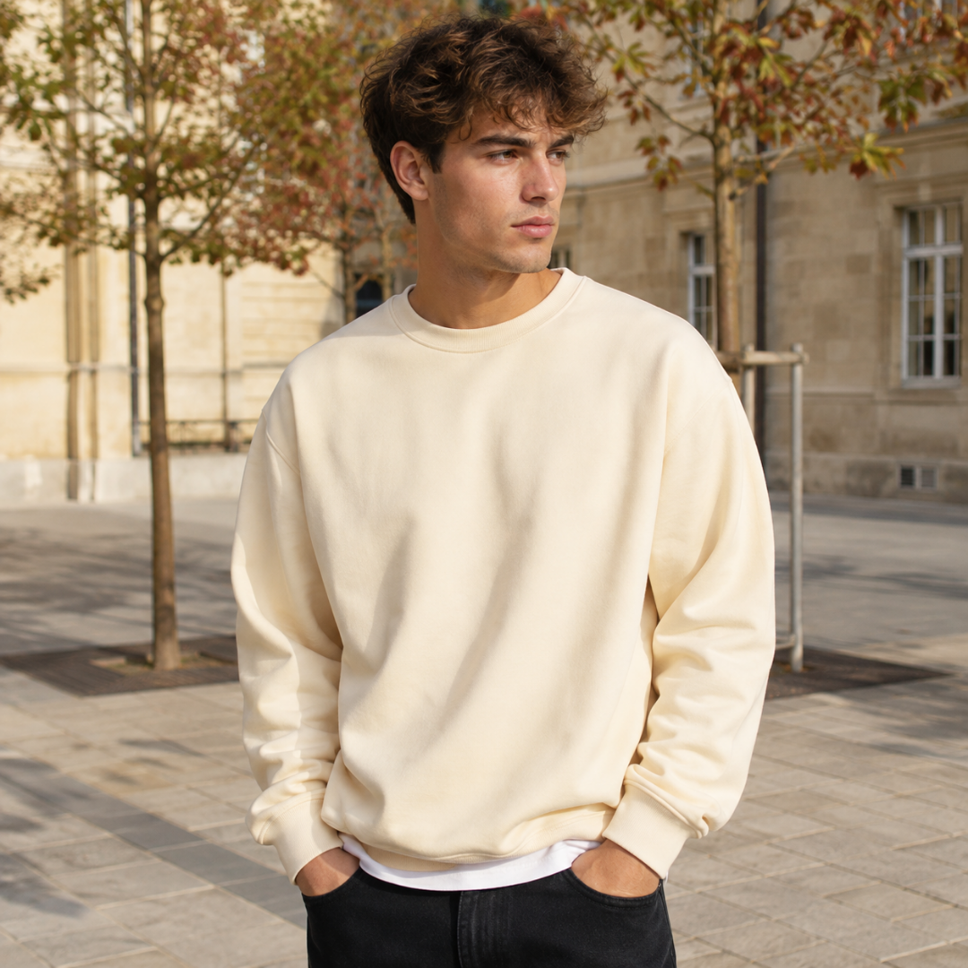 Sweat homme beige à col rond porté sur un t-shirt blanc et un pantalon noir