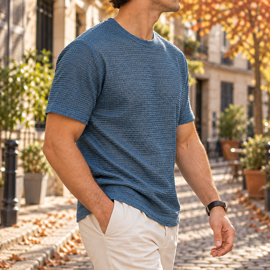 T-shirt homme bleu vu de profil, manches courtes et épaules structurées en rue ensoleillée