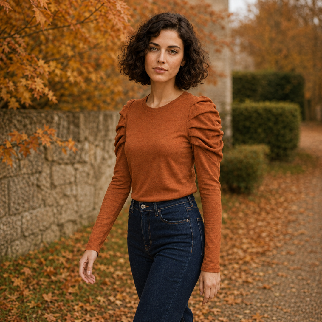 Top orange porté avec un pantalon foncé, manches longues bouffantes et buste uni
