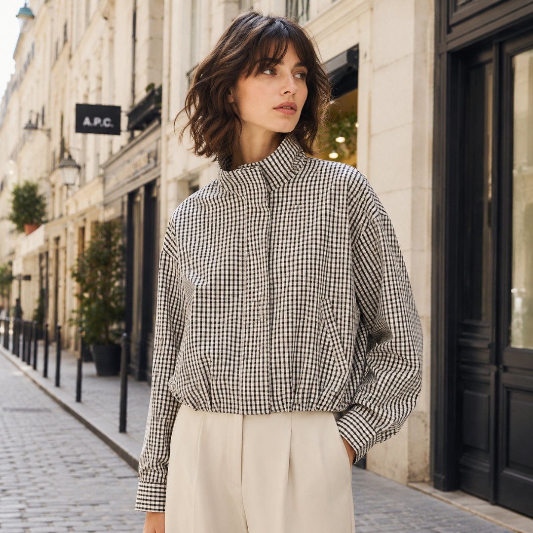 Veste à carreaux noir et blanc fermée jusqu'au col, portée sur pantalon clair en rue