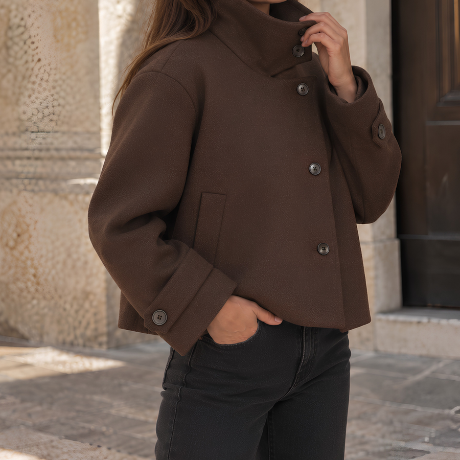 Veste courte femme chocolat à col montant et boutonnage asymétrique, portée avec jean noir