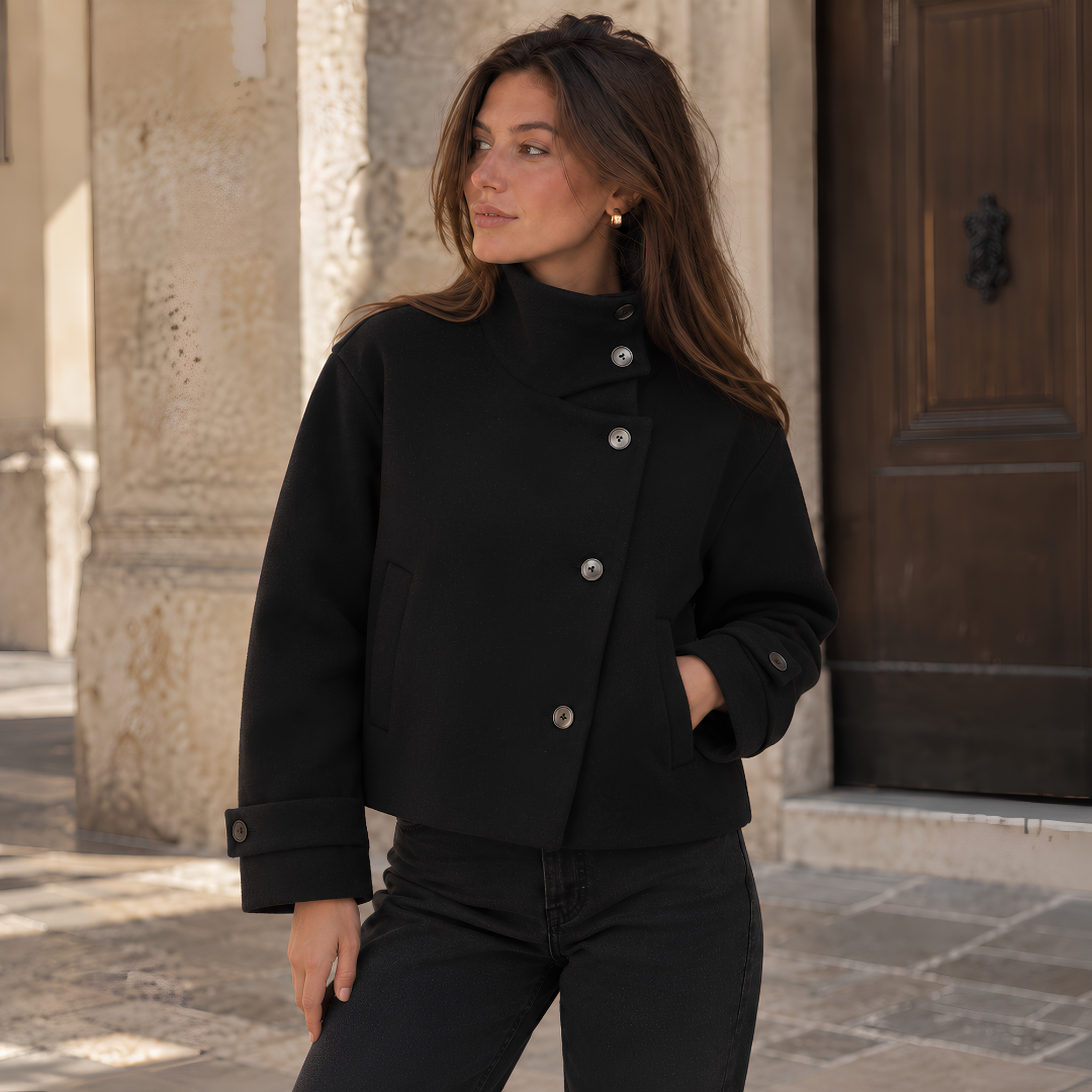 Veste courte noire à boutonnage asymétrique portée avec un pantalon noir droit