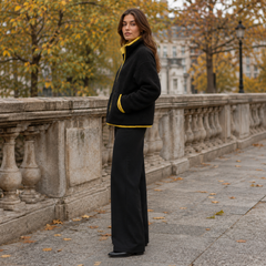 Profil de la veste noire moelleuse, ourlet et poche soulignés d'un passepoil jaune