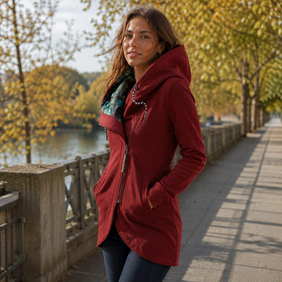 Veste rouge à capuche portée ouverte, cordons tressés et doublure imprimée feuillage