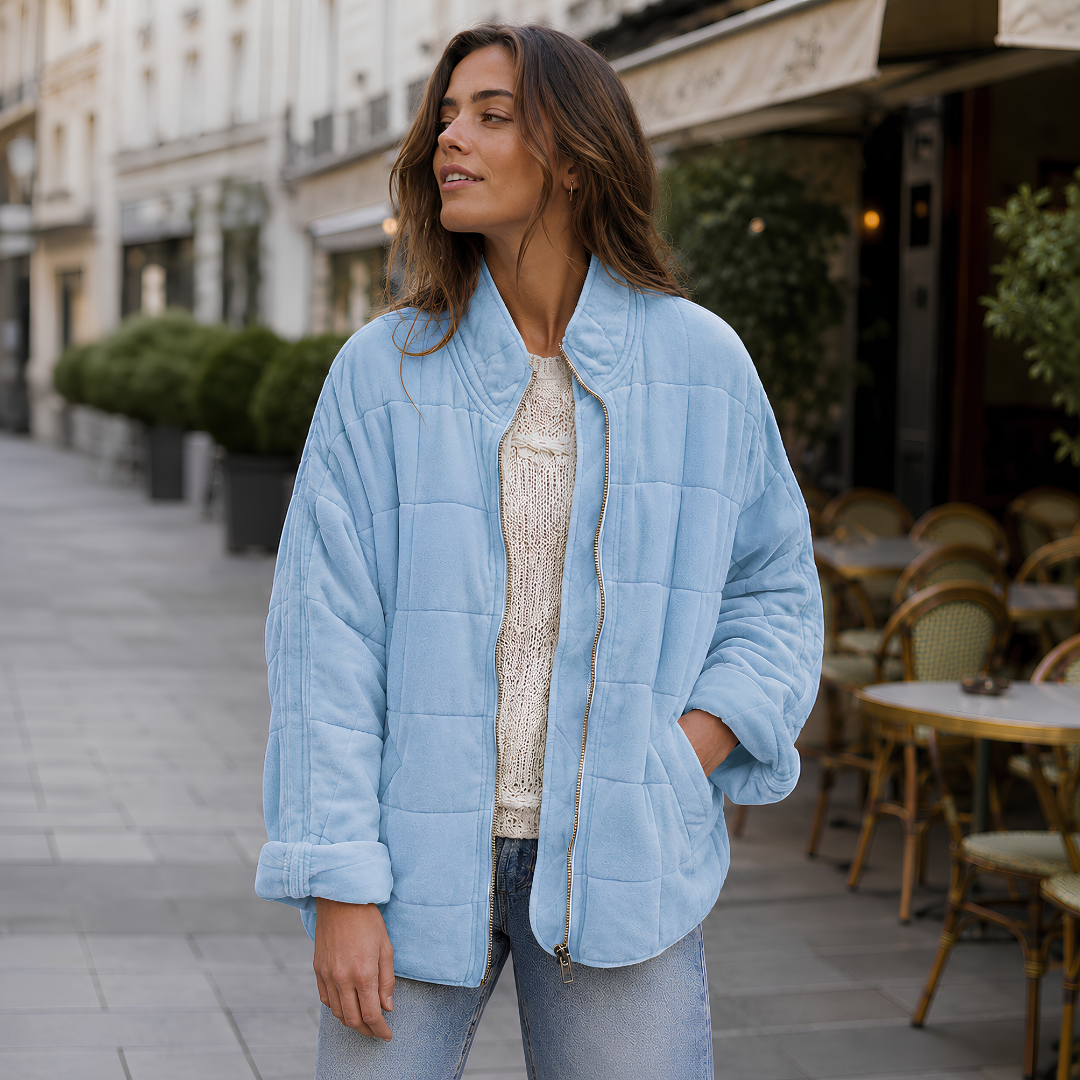 Veste matelassée bleu clair portée ouverte, manches retroussées et pantalon clair