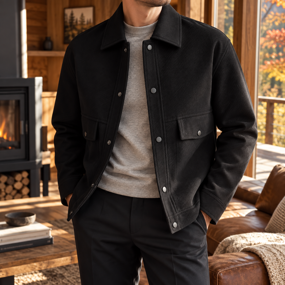 Veste homme noire à col chemise et pressions argentées, portée sur un pull gris clair